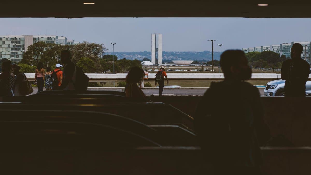 Silhouettes of people in an underpass with Brasília's National Congress in the background.