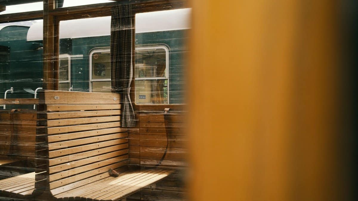 Classic wooden bench inside a vintage train with view of adjacent carriage.