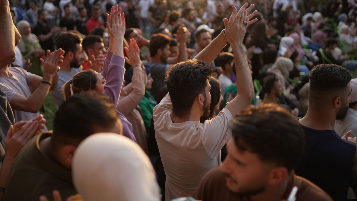 A vibrant crowd clapping together at an outdoor event, capturing unity and enthusiasm.