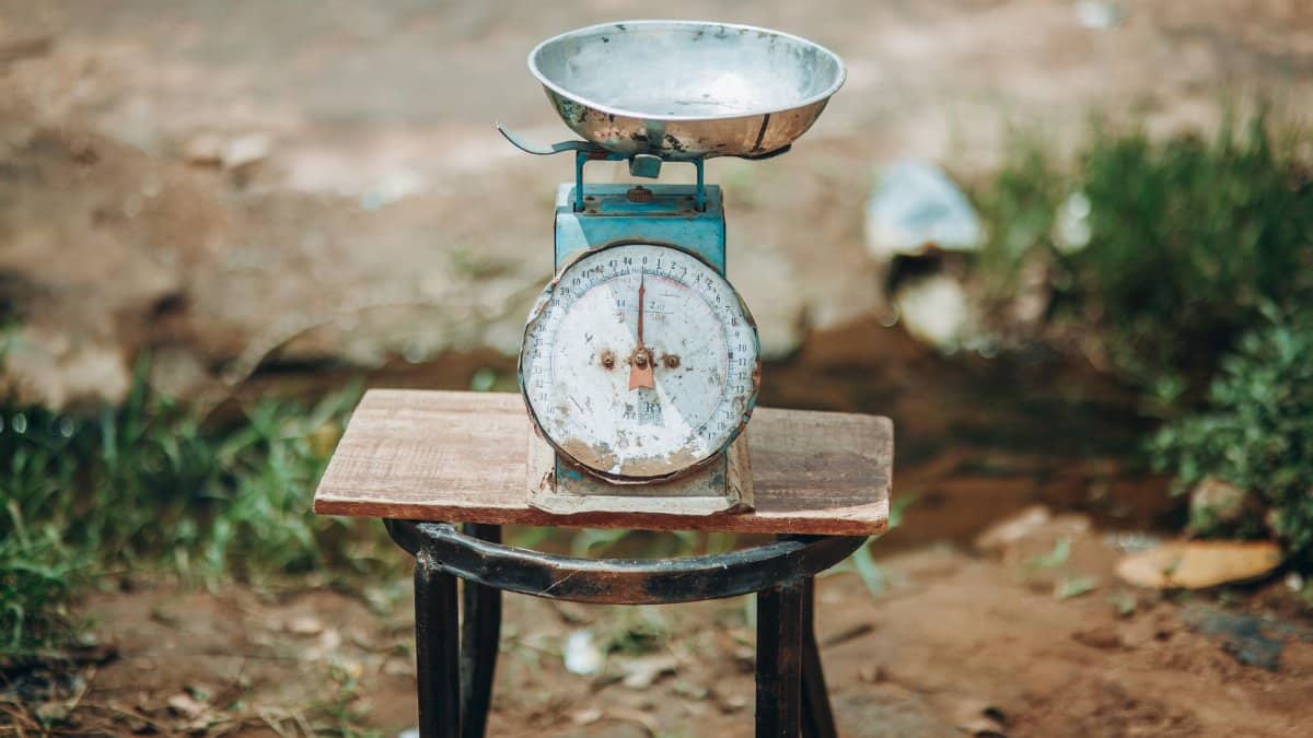 Close-up of an old-fashioned weighing scale placed outdoors on a wooden platform.