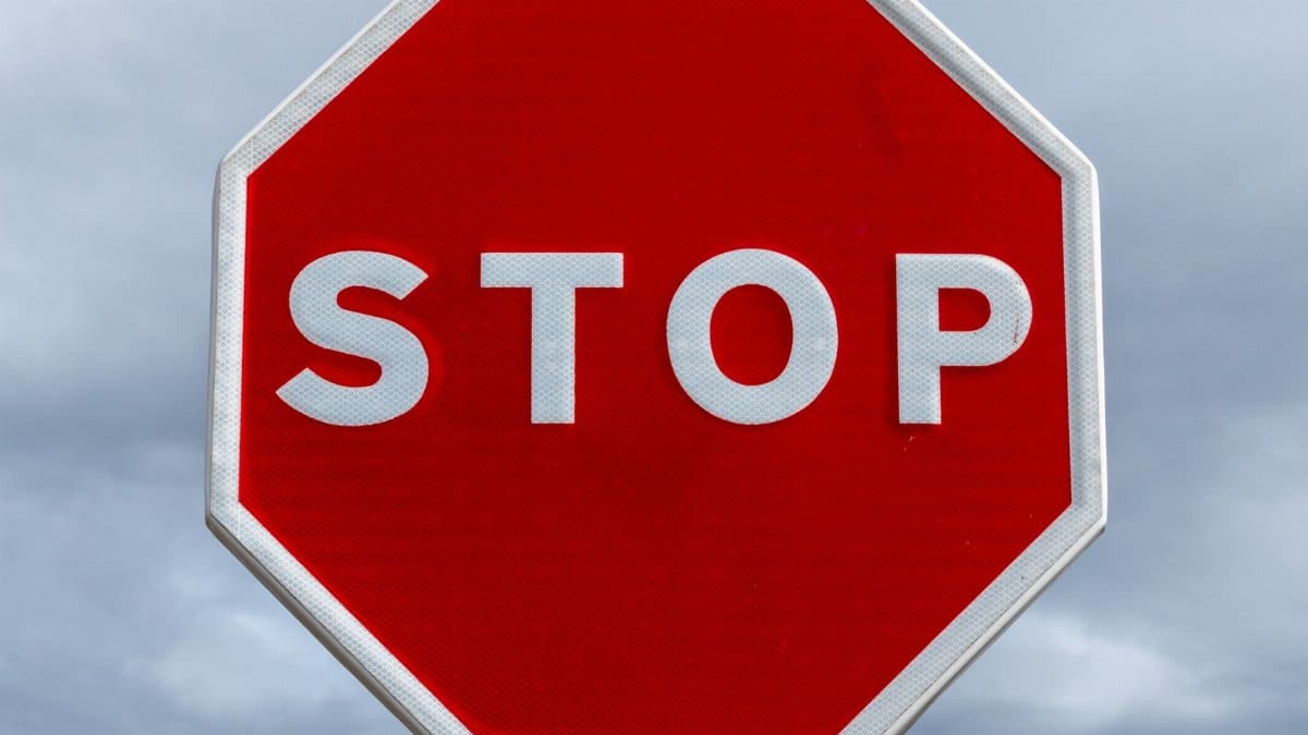 Close-up of a red stop sign with a cloudy sky backdrop, highlighting traffic regulation.