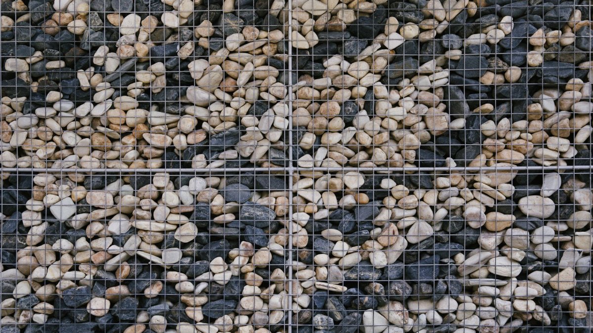 Detailed view of a stone gabion wall showcasing various colored rocks encased in a grid.