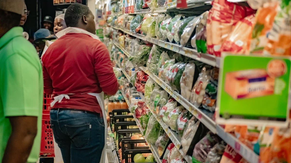 Shoppers browsing fresh produce in a busy grocery store aisle.