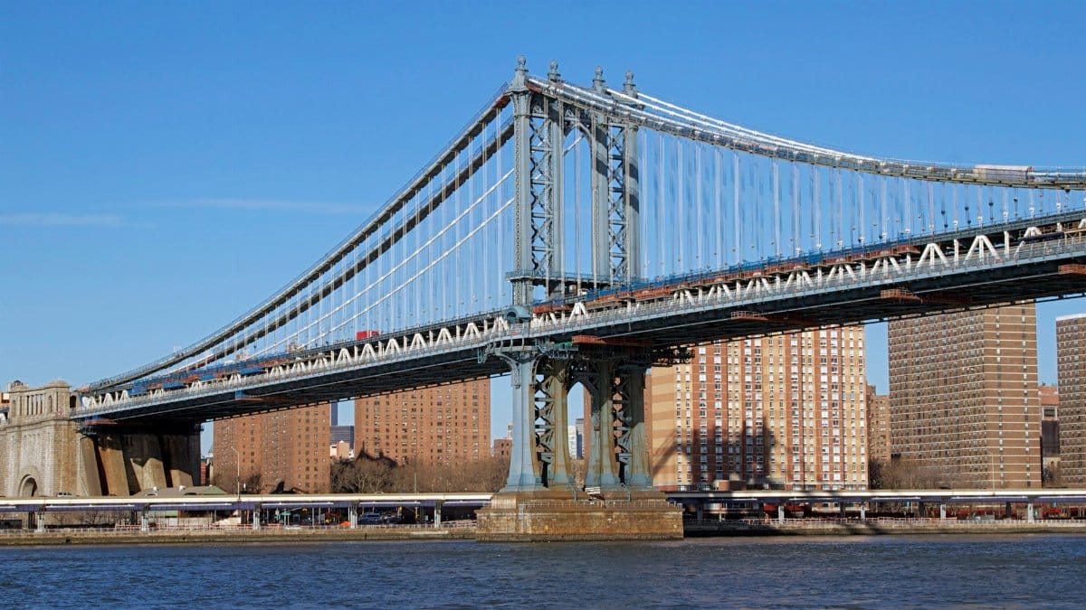 View of the Manhattan Bridge spanning the East River with New York City skyline in the background.