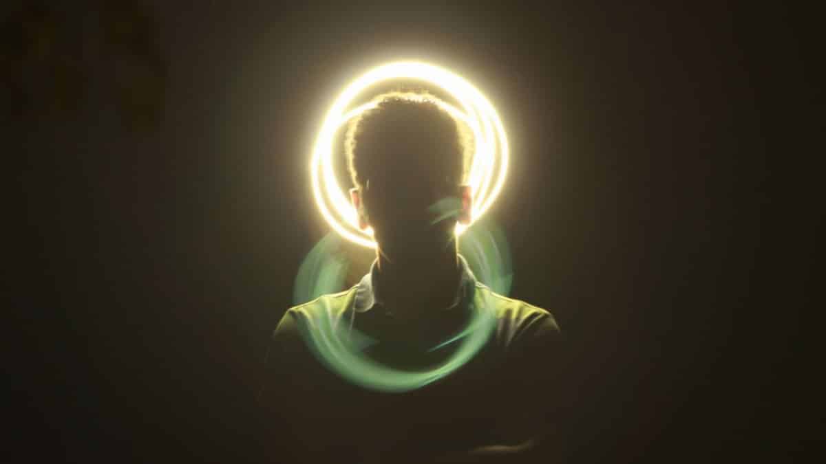 Artistic silhouette of a man with a vibrant halo light effect and motion blur on a dark background.