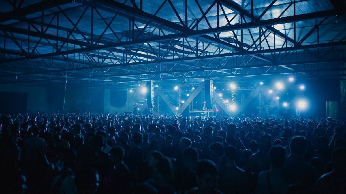 A vibrant indoor concert with a large energetic crowd enjoying the live performance.