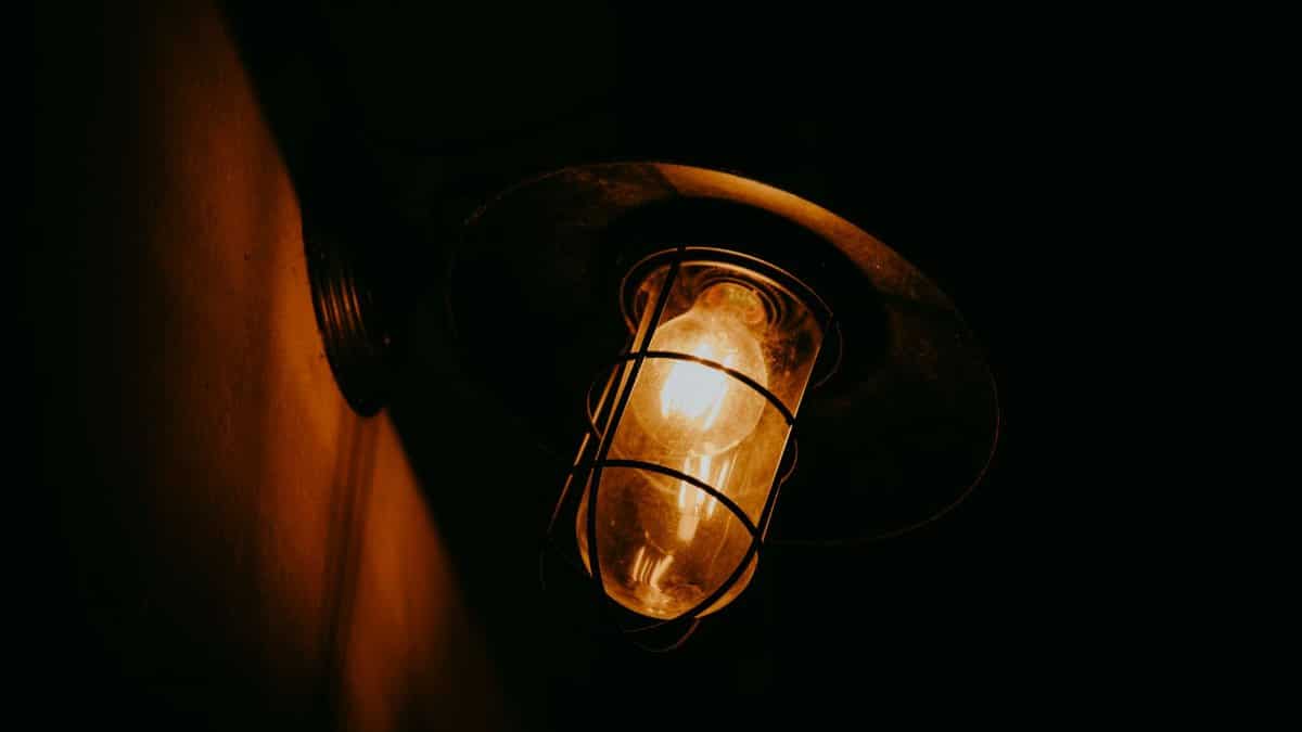 A vintage streetlamp emits a warm glow on a dark night, creating a moody ambiance.