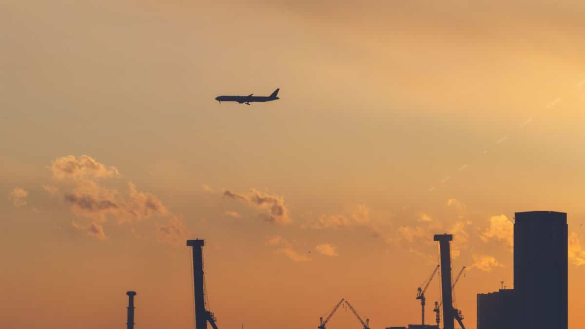 A silhouette of an airplane flying over Tokyo's skyline with a golden sunset backdrop.
