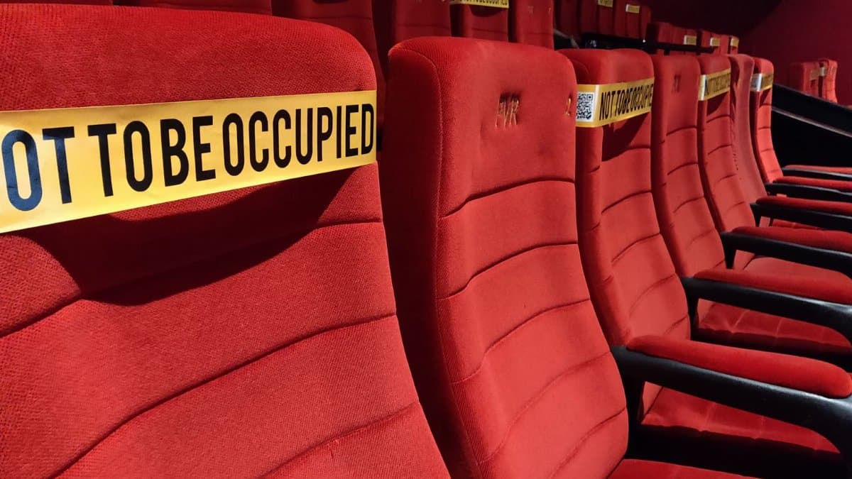 Red theater seats marked for social distancing with 'Not To Be Occupied' tape.