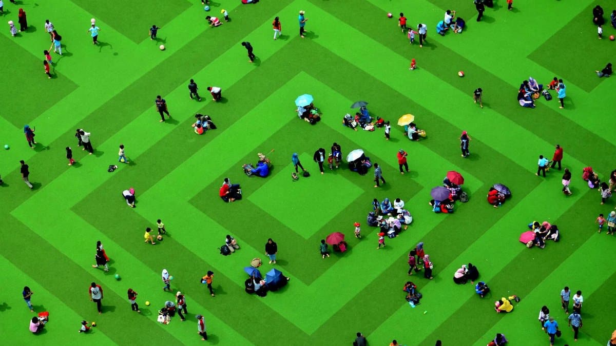 A vibrant aerial view of people gathering on a green geometric field in Bandung, Indonesia.