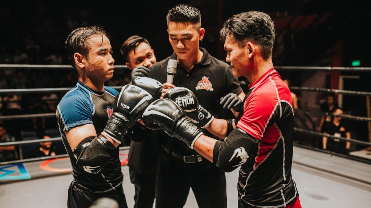 Two boxers and a referee engage in an intense pre-fight moment in the boxing ring.