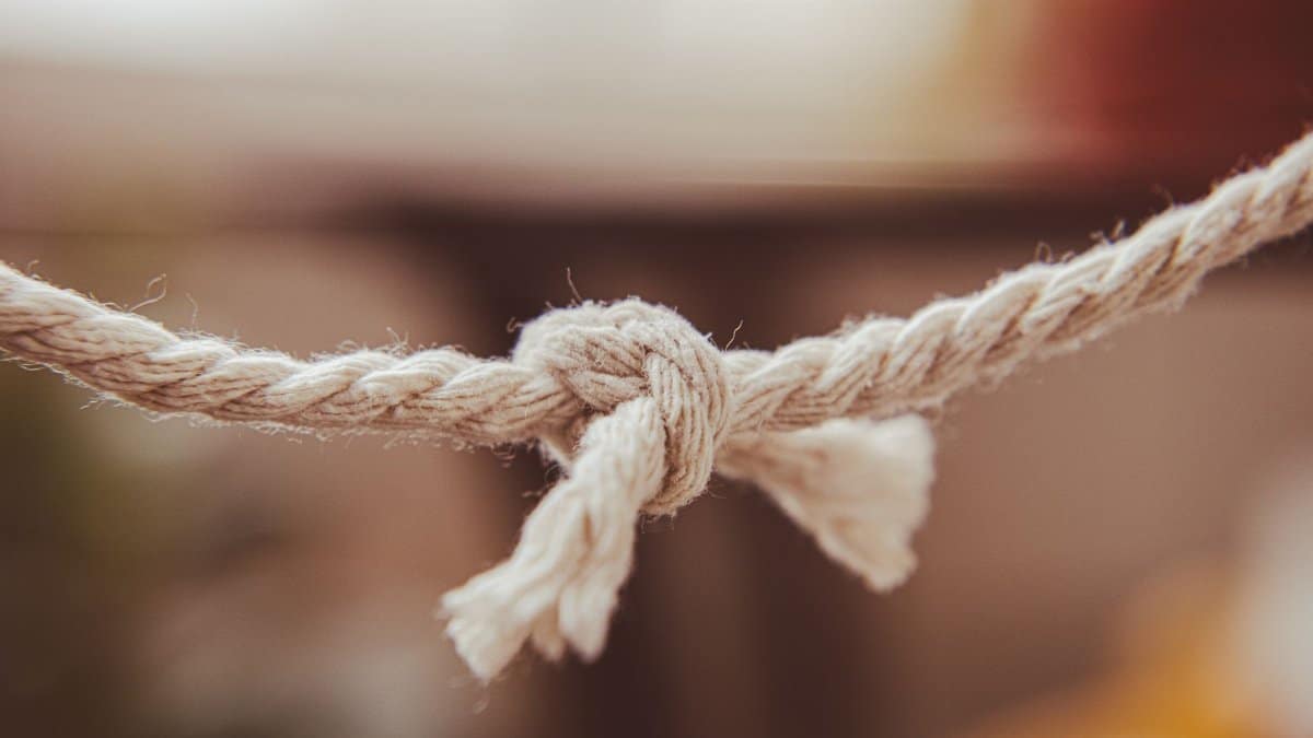 Detailed close-up of a rope with a simple knot tied, in a neutral indoor setting.