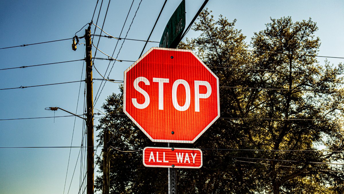 Bright red stop sign with all way label under a clear blue sky.