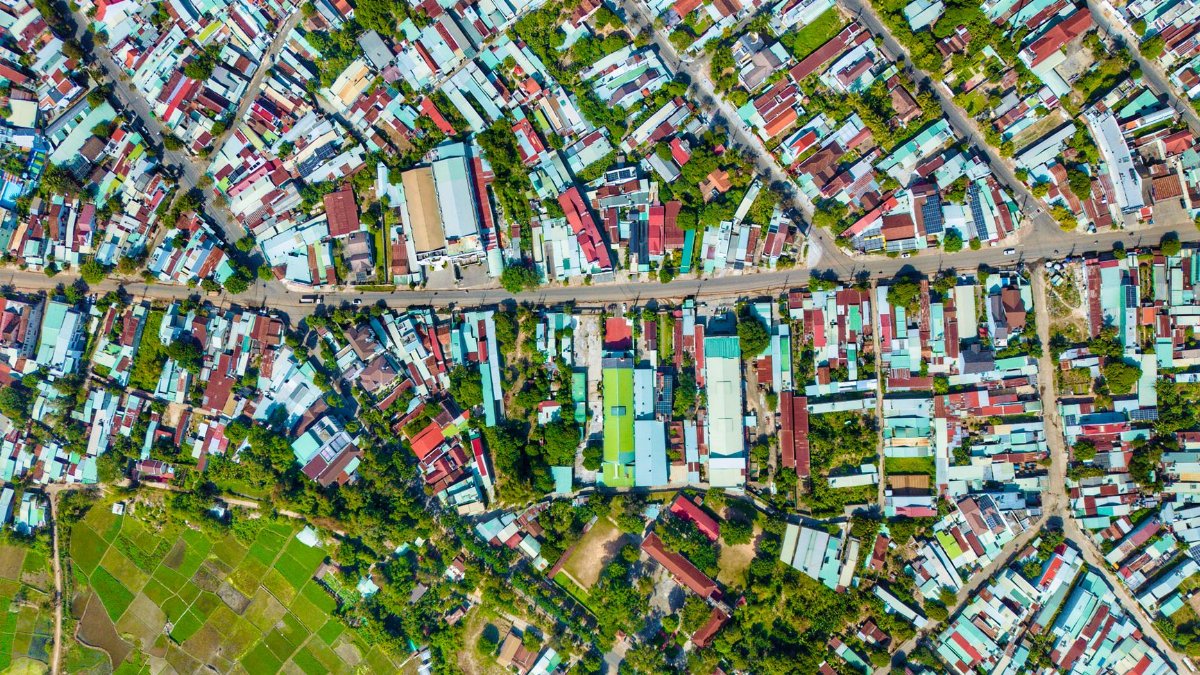 Aerial shot of a colorful urban neighborhood, showcasing tightly packed houses and greenery.