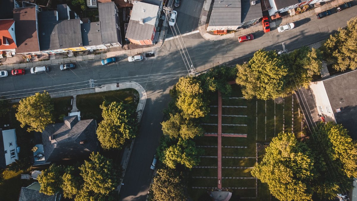 Overhead view of an urban neighborhood with streets, cars, and greenery.