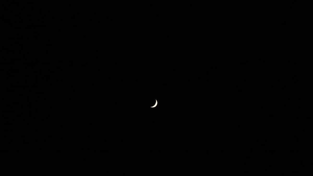 A serene crescent moon floating in a vast and dark night sky, creating a peaceful celestial scene.