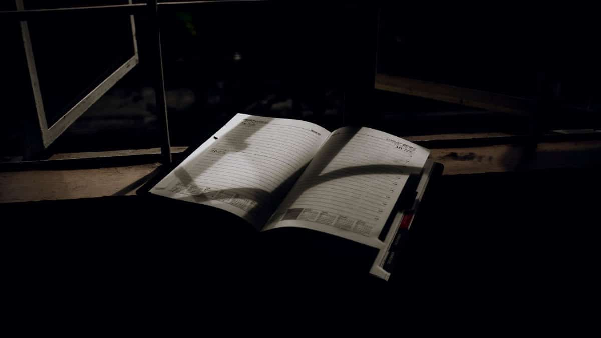An open planner with dramatic lighting sits on a window sill at night. Ideal for creative projects.