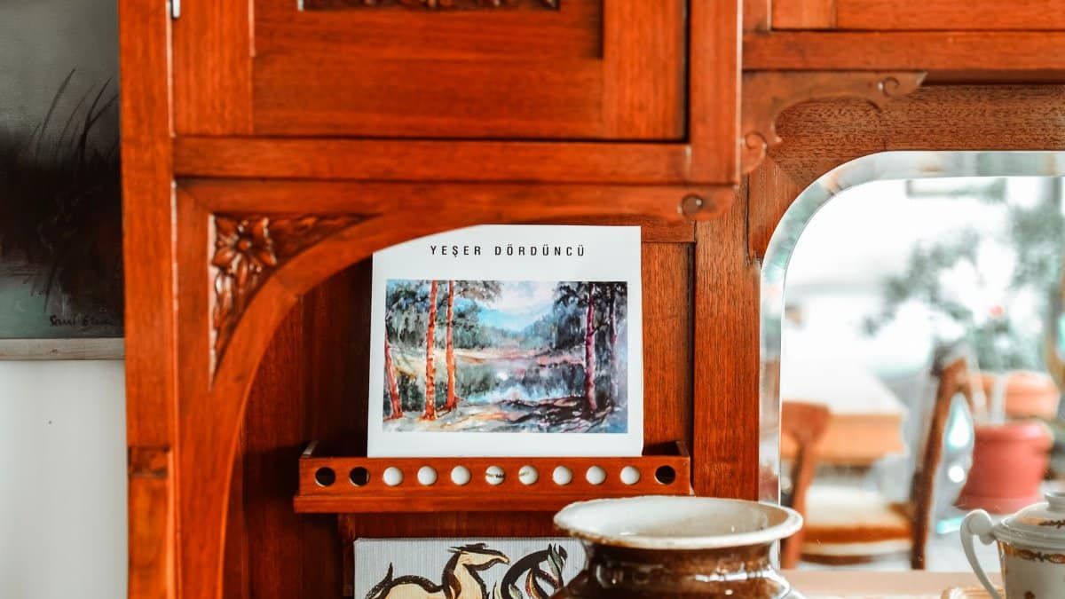 A rustic wooden cabinet showcasing artistic decor with a landscape painting and ceramics.