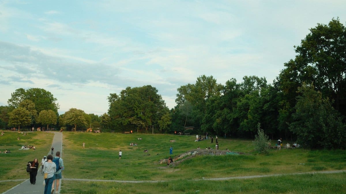 A vibrant park scene in Berlin with people relaxing and socializing under clear skies.