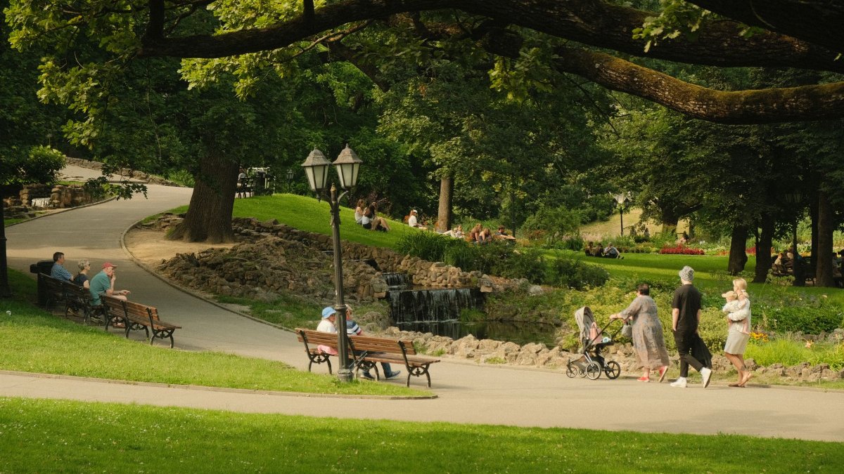 Urban park scene with lush greenery and people enjoying leisure time.