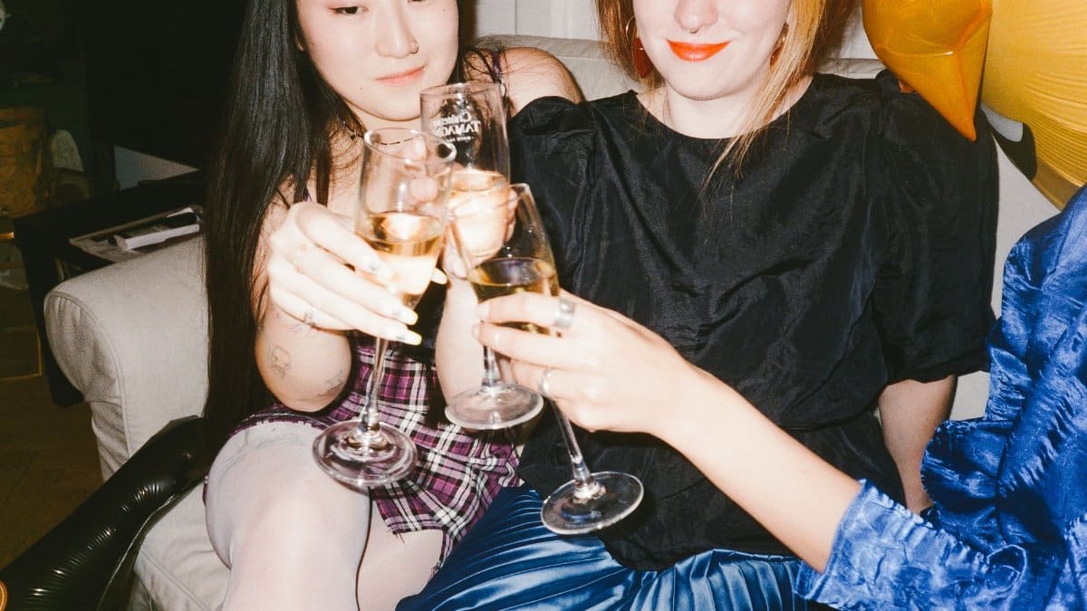Three women toasting with champagne glasses at an indoor celebration party.