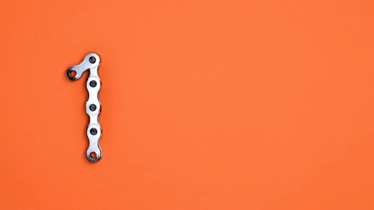Metal chain forming the number one on an orange background, ideal for design concepts.