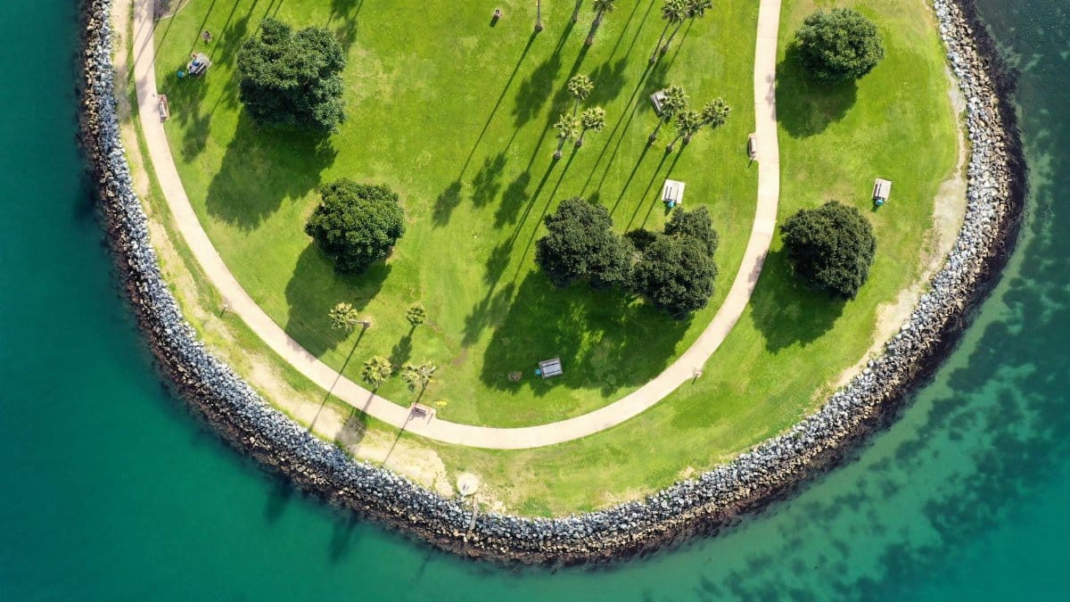 A stunning birds-eye view of a lush green park on a peninsula surrounded by blue water.