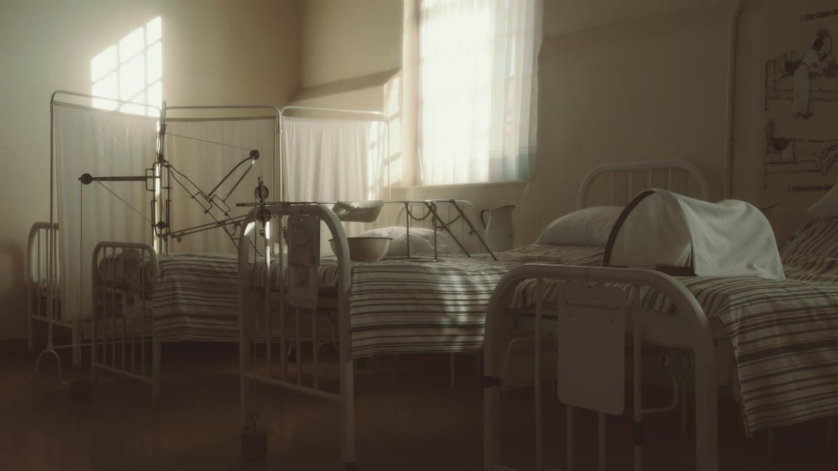 Dimly lit vintage hospital room featuring empty beds and medical equipment, creating a nostalgic atmosphere.