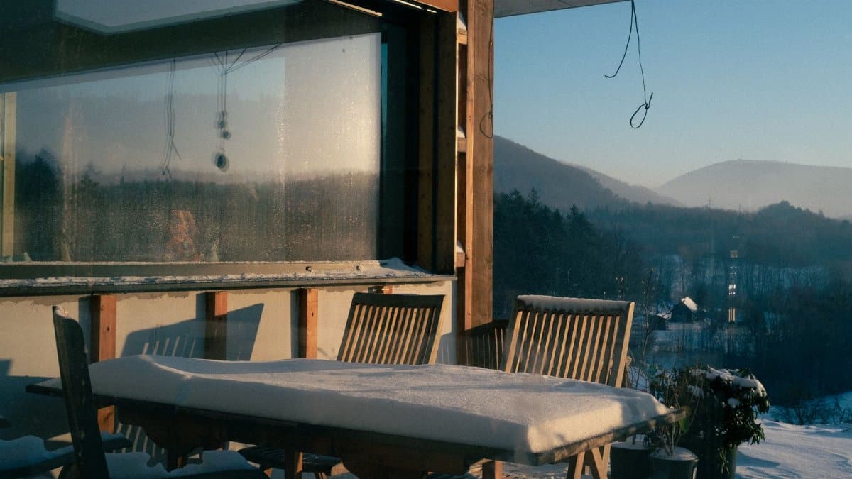 Snow-covered porch overlooking mountains, capturing a serene winter landscape.