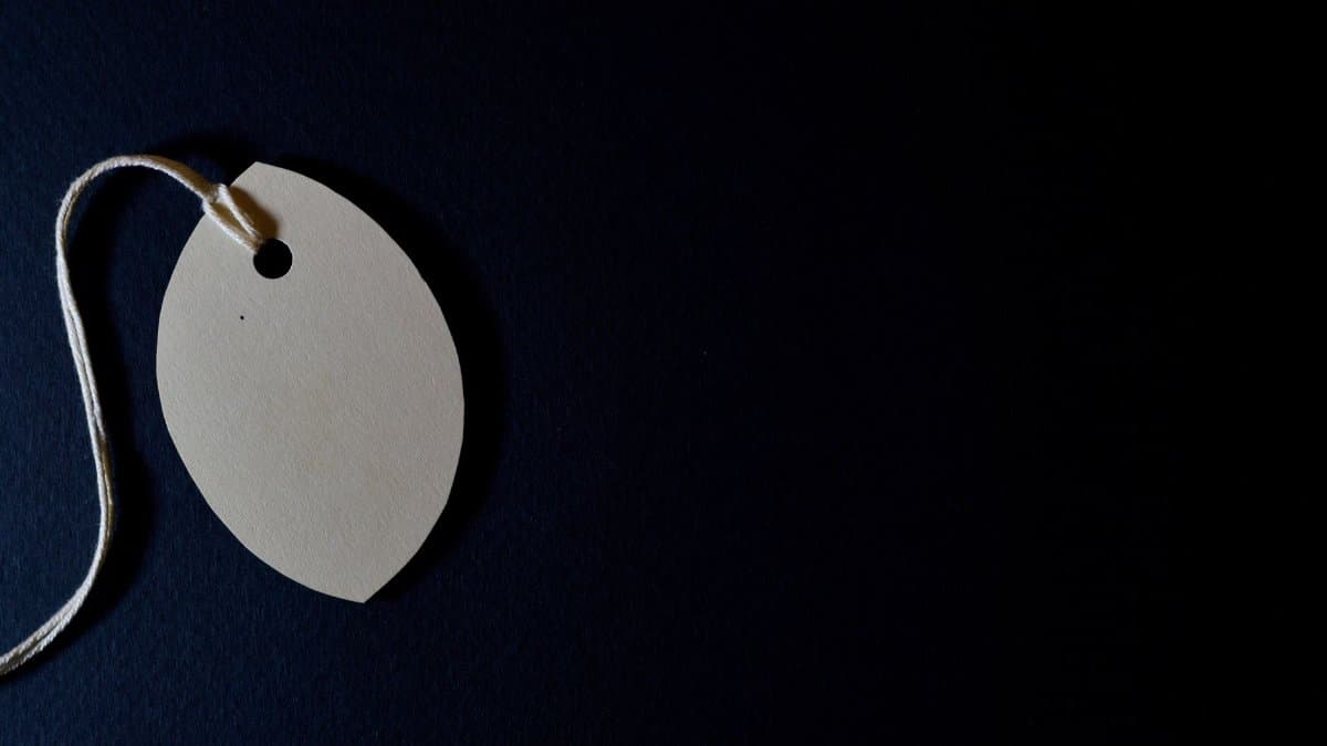 Close-up of a blank paper tag with string on a dark background, perfect for customizable designs.