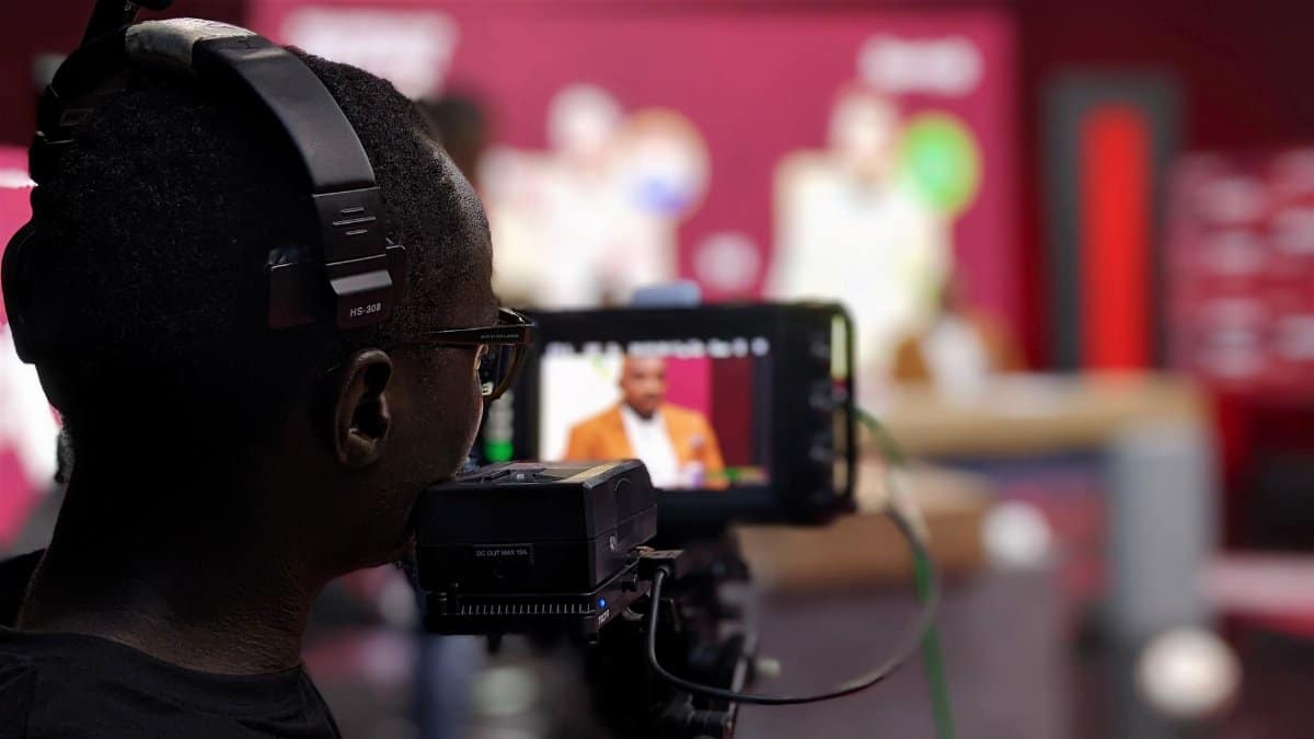 Close-up of a cameraman with headphones filming a program in a studio setting.