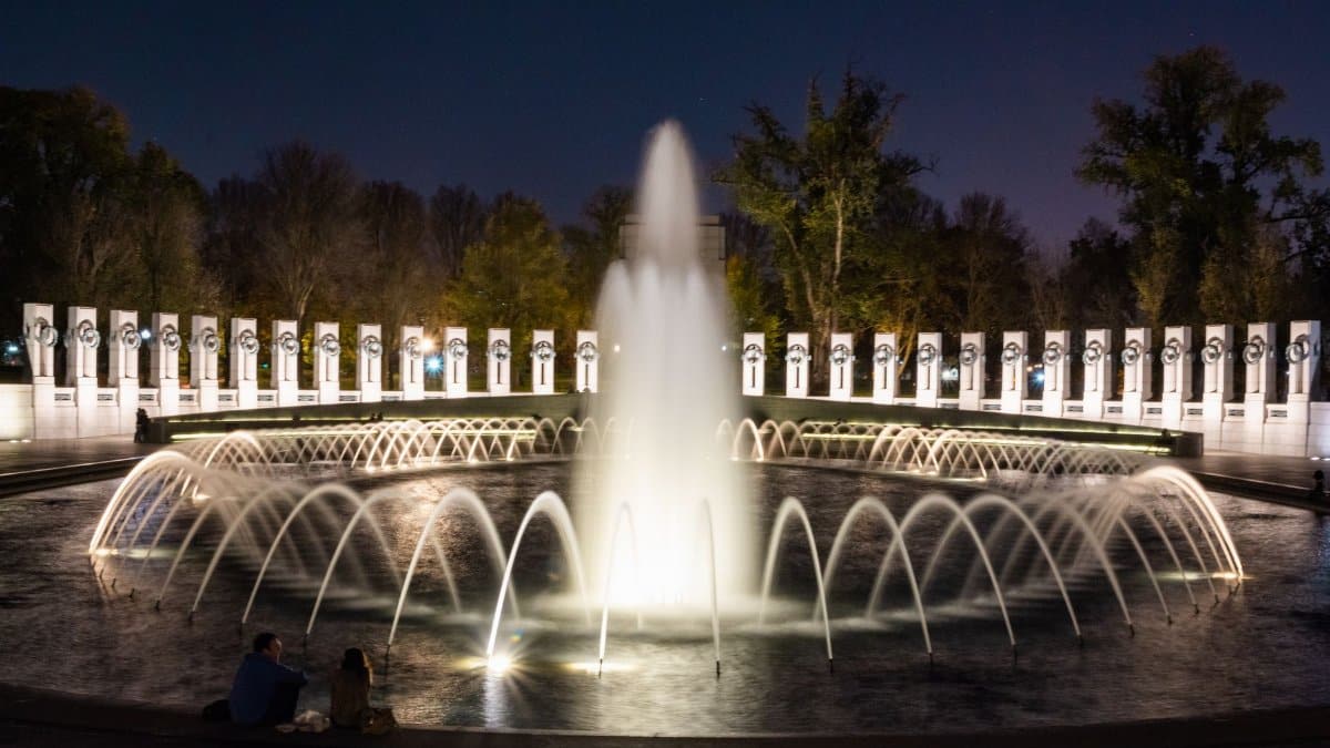 Long exposure of the World War II Memorial fountain at night in Washington D.C. showcasing its vibrant illumination.