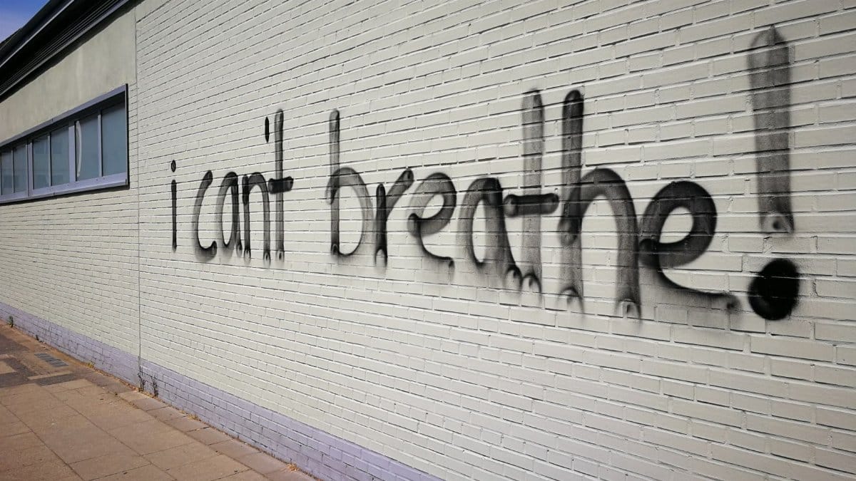 Graffiti text 'I can't breathe' on a brick wall, symbolizing protest.