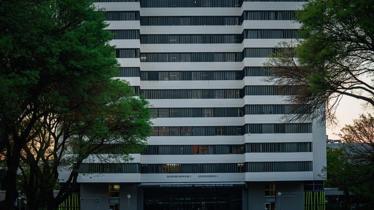 Modern university building exterior in Pretoria surrounded by trees.
