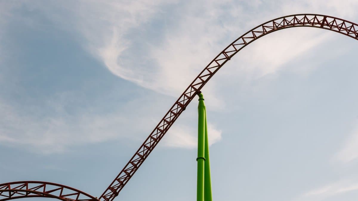 Dramatic roller coaster track against a clear blue sky, capturing the thrill of amusement parks.