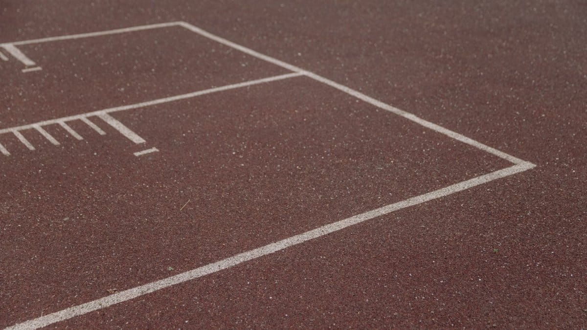 Detailed view of red athletics track with white lines and markings.