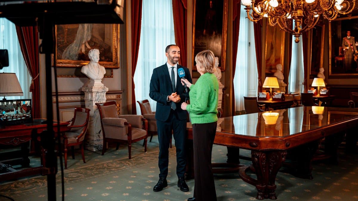 A professional interview in a luxurious, historical room with rich decor and art.