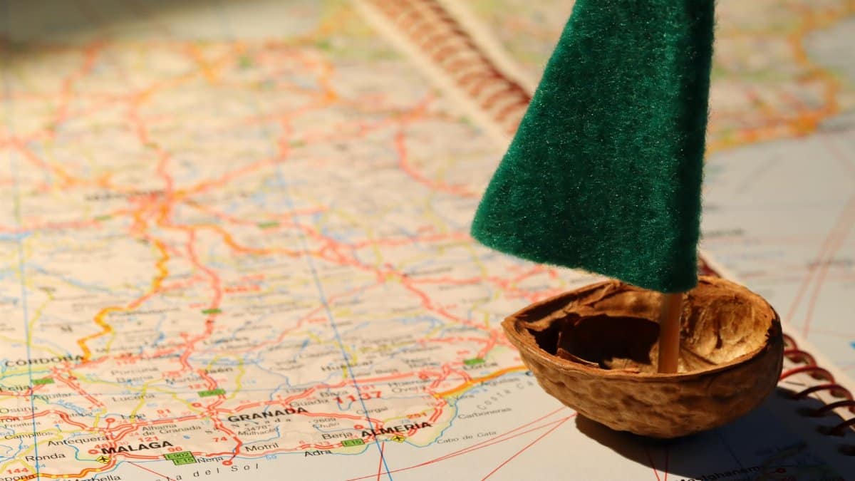 Creative travel metaphor with a tiny sailboat on a detailed world map.