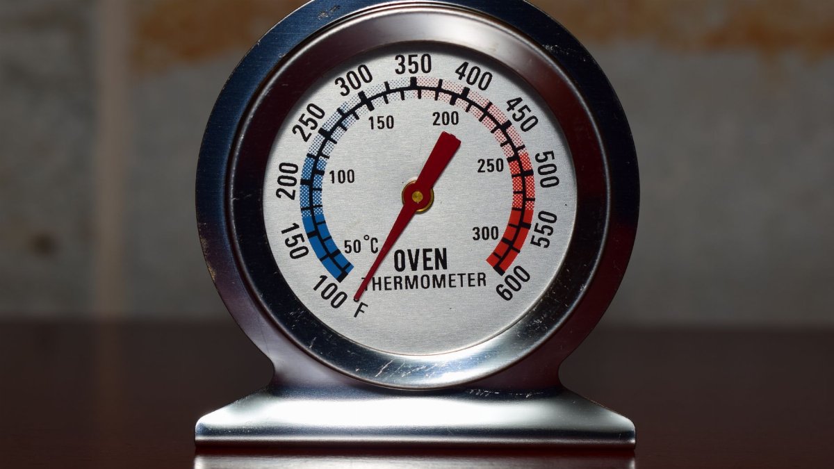 Close-up of a metallic oven thermometer showing temperature in Celsius and Fahrenheit.