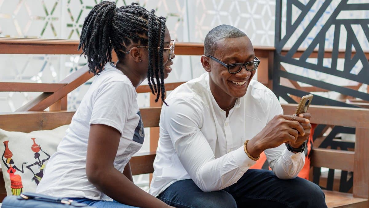 Smiling African couple sharing phone moments at a cafe in Accra, Ghana.