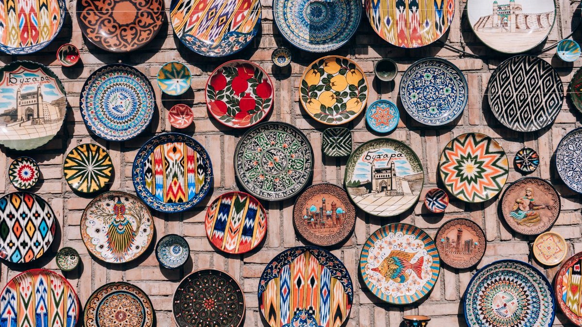 Vibrant ceramic plates on a brick wall in Bukhara, showcasing traditional Uzbek art and design.