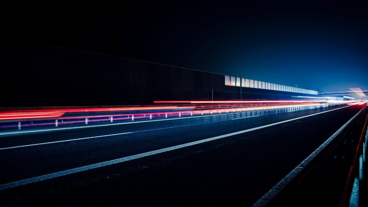 Vibrant long exposure photo capturing light streaks on a highway at night, illustrating speed and motion.