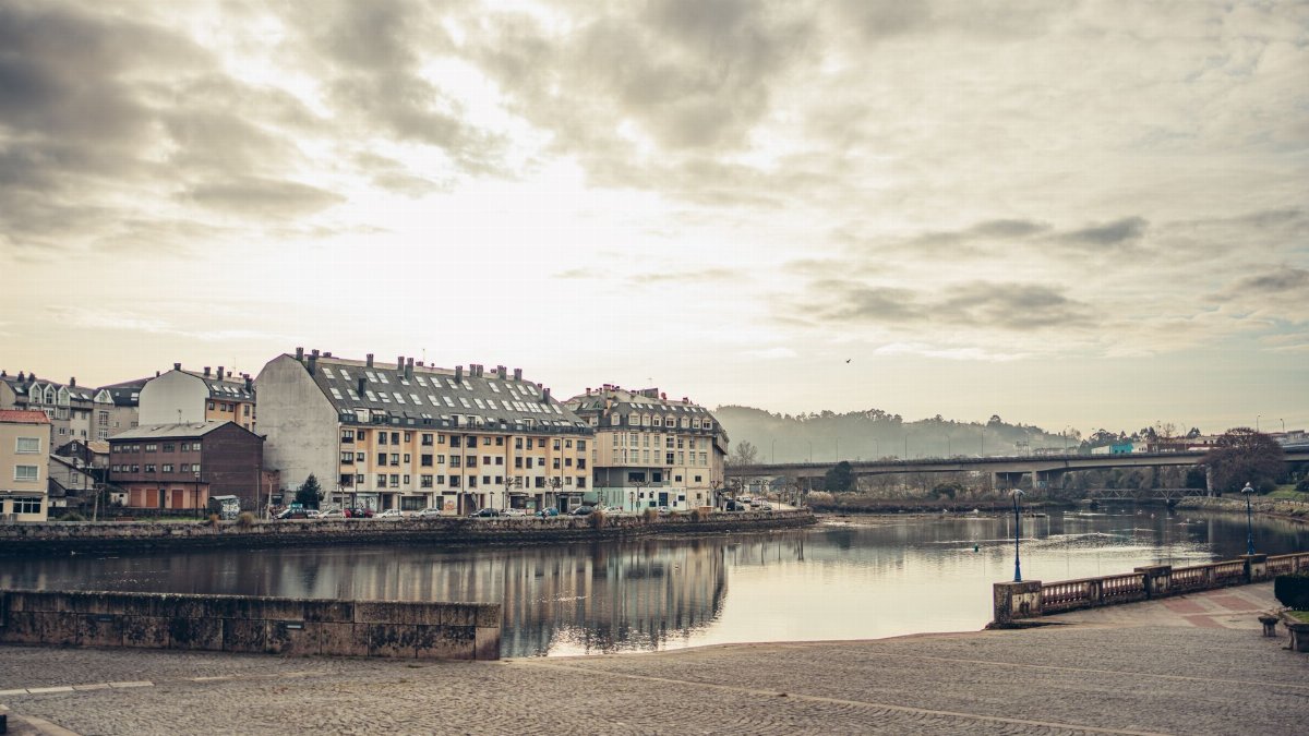 Tranquil river view with picturesque buildings and cloudy sky in Burgo, Spain.