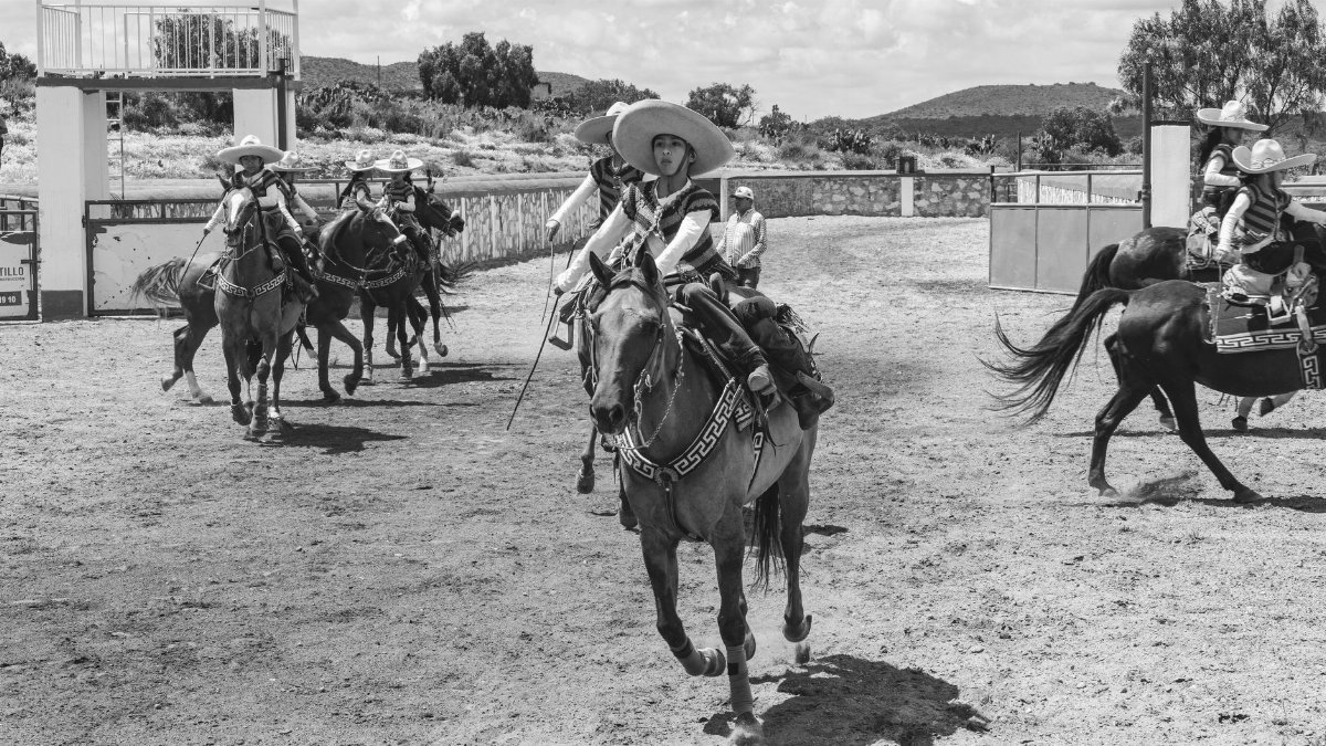 Traditional Mexican charros riding horses in a rural rodeo arena, San Juan Tizahuapan.