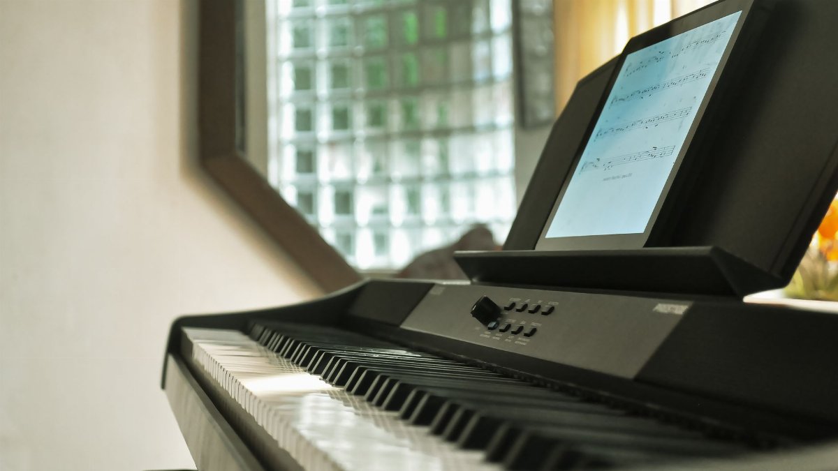Close-up of a digital piano with a music sheet display in a well-lit room.