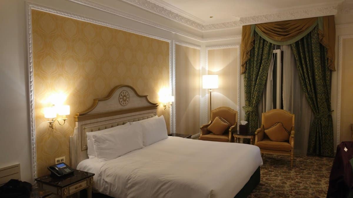Luxurious hotel room featuring a king-sized bed, elegant furnishings, and ambient lighting.