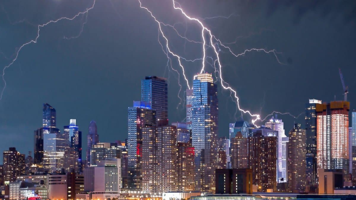 Thrilling lightning storm over a bustling urban skyline at night with stunning reflections on the waterfront.