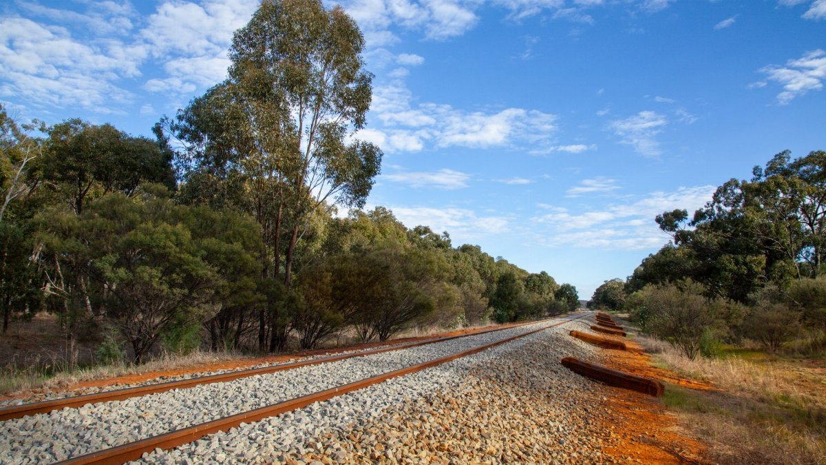 Railway line through Australian bushland under a vibrant blue sky in New South Wales.