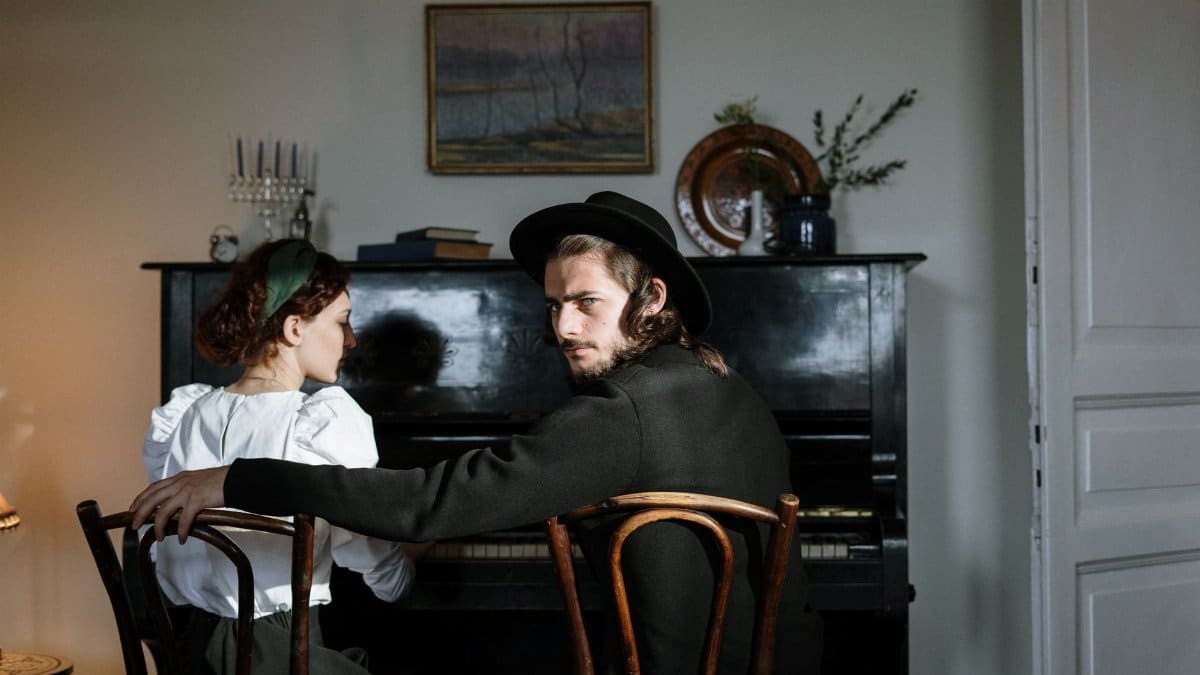 Orthodox Jewish couple sitting together at a piano in a cozy home setting, reflecting love and tradition.