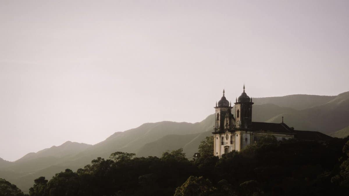 Captivating view of a historic church set against the mountains of Ouro Preto, Brazil, during sunset.